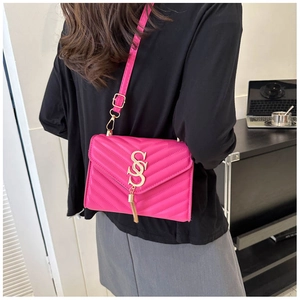 Detail of fuchsia quilted crossbody bag with gold SSS logo and tassel on model