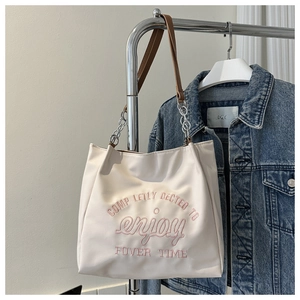 Detail of off-white tote bag with pink 'enjoy' embroidery and chain leather handle