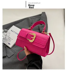Detail of rose red faux crocodile leather handbag with ornate golden baroque buckle strap
