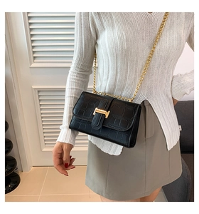 Detail shot of black stone-pattern bag with gold H-buckle and elegant chain strap