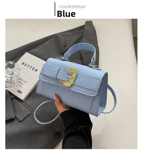 Detail of light blue crocodile embossed handbag with vintage golden baroque buckle