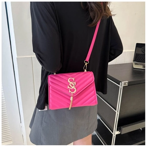 Detail view of a fuchsia chevron quilted crossbody bag with a gold tassel and metal logo