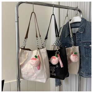 Close-up of three canvas tote bags with 'enjoy' embroidery and peach plush pendants