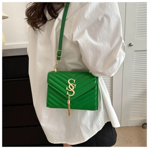 Detail of green quilted PU leather crossbody bag with gold logo and metal tassel