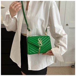 Detail of bright green quilted crossbody bag with gold SS logo and tassel charm