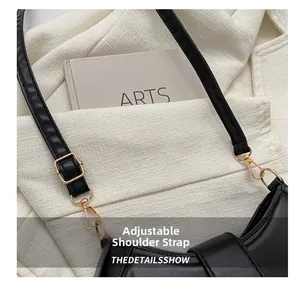 Detail of black leather saddle bag showing adjustable shoulder strap with gold metal buckle