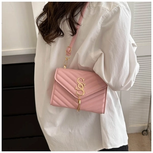 Detail of pink quilted crossbody bag with golden S-logo and fringe on a female model