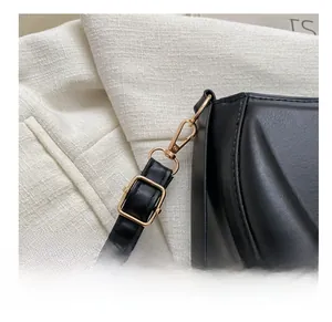 Detail of matte black leather saddle bag featuring a gold metal hook and fine stitching
