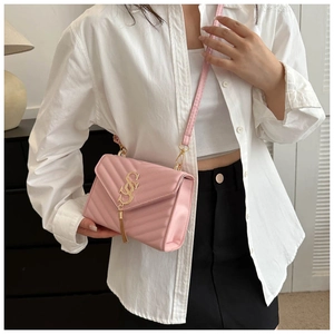 Close-up of pink quilted crossbody bag with gold SS logo and elegant metal tassel detail
