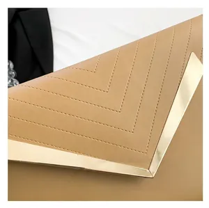 Dettaglio macro della trapuntatura a V e bordo in metallo dorato su pochette beige