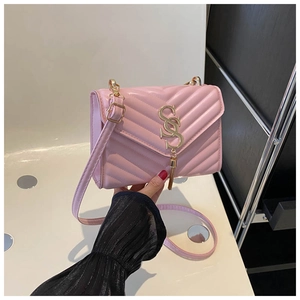 Detail view of pink quilted handbag featuring V-pattern stitching and gold metal buckle