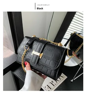Detail view of black crocodile pattern crossbody bag with gold metal buckle and chain strap
