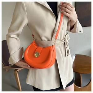 Detail of bright orange saddle bag featuring a golden metal buckle and smooth PU leather