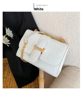 Detail view of a white crocodile texture bag with a gold H-shaped clasp and chain strap