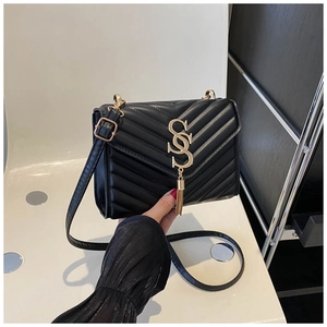 Close-up of black quilted PU bag featuring golden metal logo and elegant tassel detail