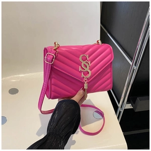 Close-up of quilted rose pink crossbody bag with gold V-pattern and tassel detail