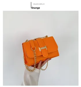 Detail view of orange crocodile texture bag featuring gold H-shaped clasp and chain strap