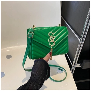 Close-up of green quilted leather bag featuring a gold S logo and elegant metal tassel