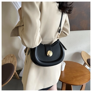 Detail of a black hobo bag featuring a large gold metal buckle on the shoulder strap