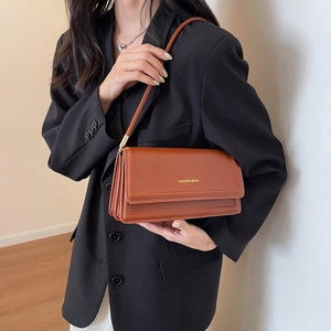 Caramel brown leather underarm bag with multi-layer accordion design and gold lettering