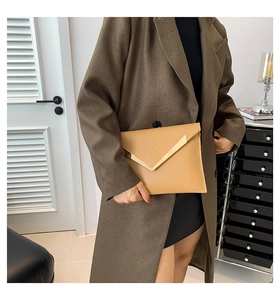 Détail d'une pochette enveloppe kaki avec garniture en métal doré en V et coutures