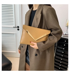 Détail d'une pochette enveloppe kaki avec garniture en métal doré en V et coutures en cuir