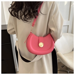 Detailed view of a rose pink saddle bag with gold buckle on a cream wool coat