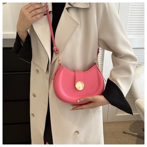 Close-up of pink saddle bag with golden metal buckle worn on a beige trench coat