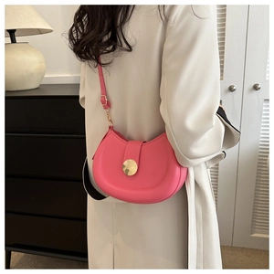 Detail of fuchsia saddle bag featuring a large gold circular buckle and slim leather strap