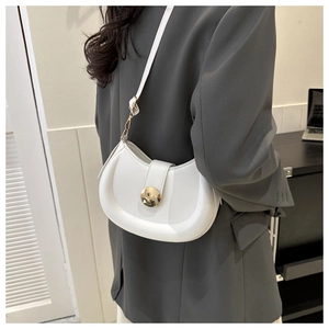 Detail of white saddle bag with golden circular buckle and thin leather shoulder strap