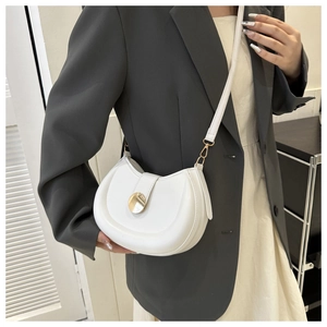 Detailed view of a white crescent saddle bag with gold metal buckle on a grey suit model