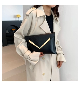 Détail de pochette enveloppe en cuir noir avec bordure métallique dorée en V et coutures