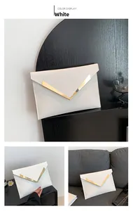 Detalle de bolso de sobre blanco con adorno en V dorado y acabado en cuero sintético