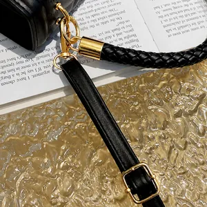 Detailed close-up of golden metal hooks on a black quilted leather handbag