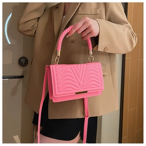 Detail of neon pink crossbody bag with V-quilted texture and woven top handle