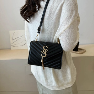 Classic black quilted crossbody bag with gold hardware and tassel detail worn by a model