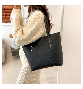 Close-up of quilted pattern and gold rivet detail on black large capacity tote bag