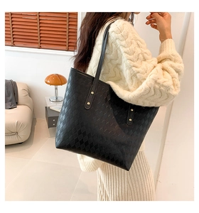 Close-up of black quilted tote bag texture with gold rivet hardware details