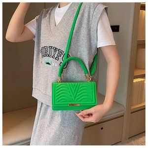 Detail of green quilted crossbody bag with woven handle and gold hardware accents
