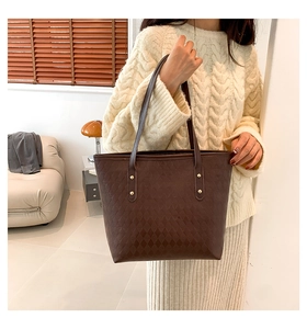 Close-up of dark brown quilted tote bag with gold rivets and leather shoulder straps
