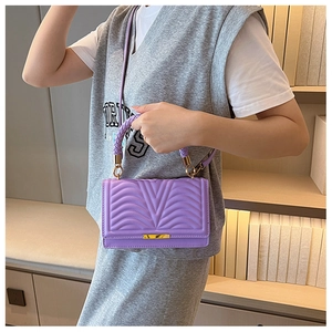 Detail of purple quilted handbag showing V-pattern texture and gold metal clasp hardware
