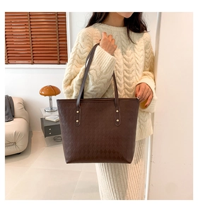 Detail of dark brown tote bag with diamond embossed texture and golden rivets