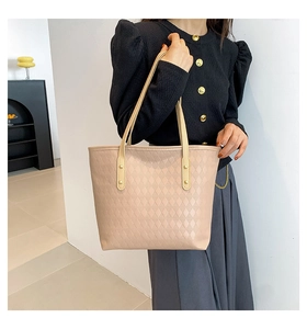Close-up of beige quilted tote bag with diamond lattice pattern and gold rivet details