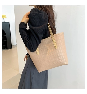 Detail view of beige quilted tote bag featuring padded diamond texture and gold hardware