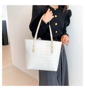 Detail of white quilted tote bag featuring fine stitching and gold rivet accents