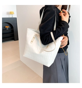 Side view of model wearing a white quilted tote bag with woven texture and beige straps