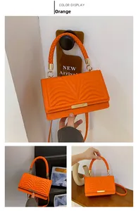 Detail of orange handbag with wave stitching, woven handle and gold metal fastener