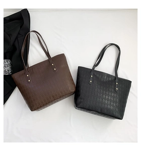 Detail of quilted tote bags in brown and black with gold rivets and double straps