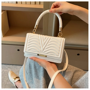 Detail of white quilted handbag with braided handle and gold metallic ring hardware