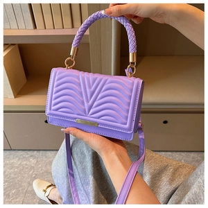 Detail of purple quilted small square bag with V-shaped texture and woven handle